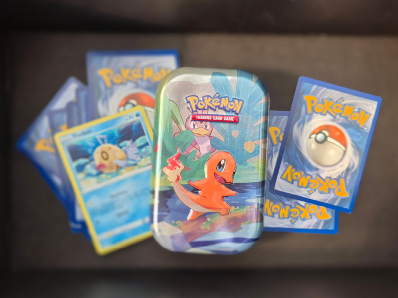 Pokémon-kort og en lille samledåse med Charmander.