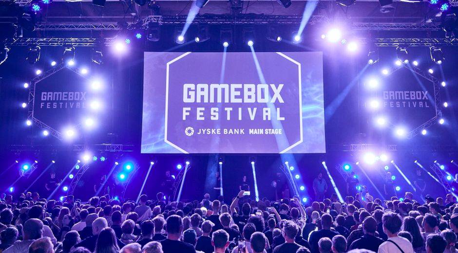 Arkivfoto af Gamebox Festivals scene med publikum og blå og lilla scenebelysning.